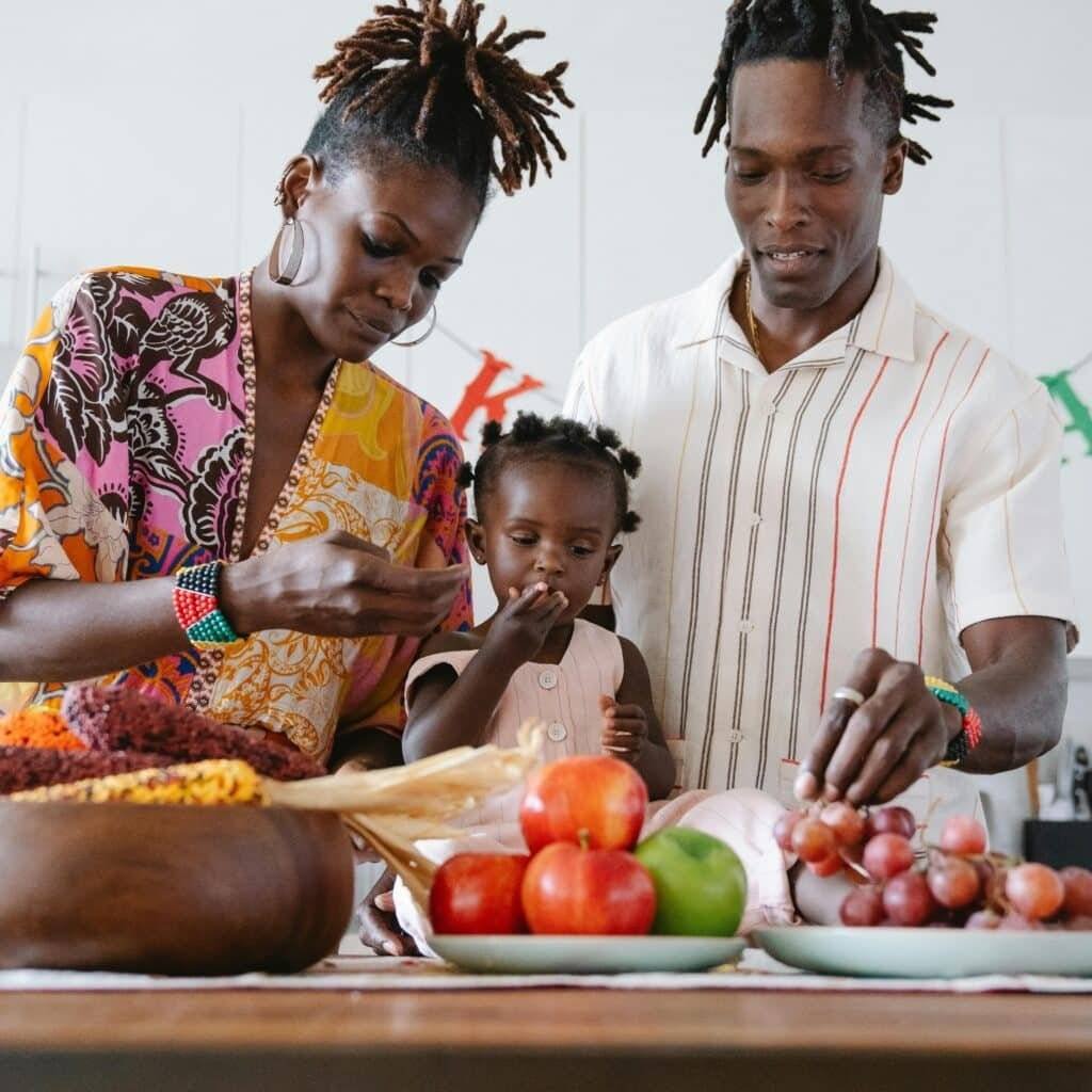 A family bonds over fruits in an indoor kitchen, creating joyful moments together.