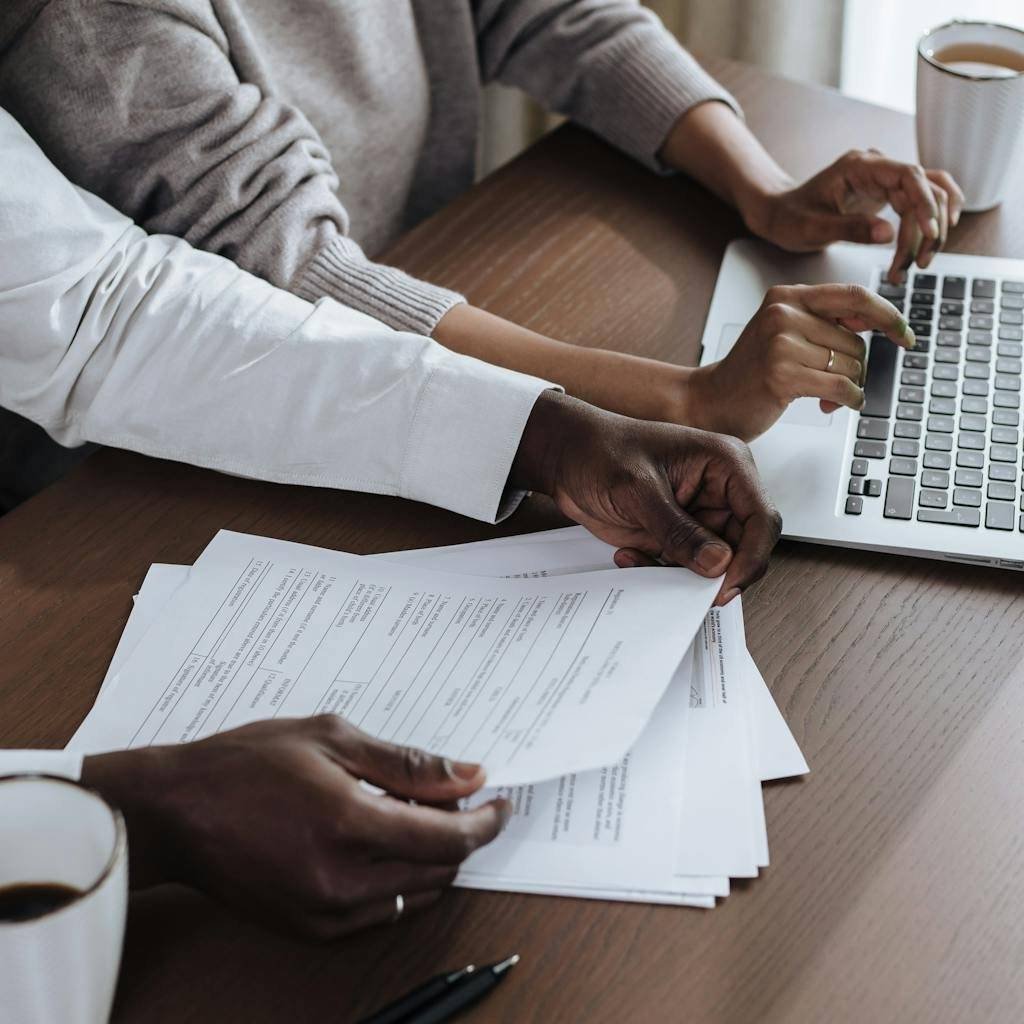 Close-up of diverse colleagues working together on a laptop in a modern office environment.