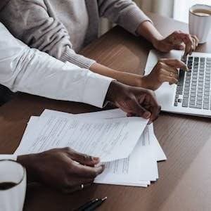 Close-up of diverse colleagues working together on a laptop in a modern office environment.