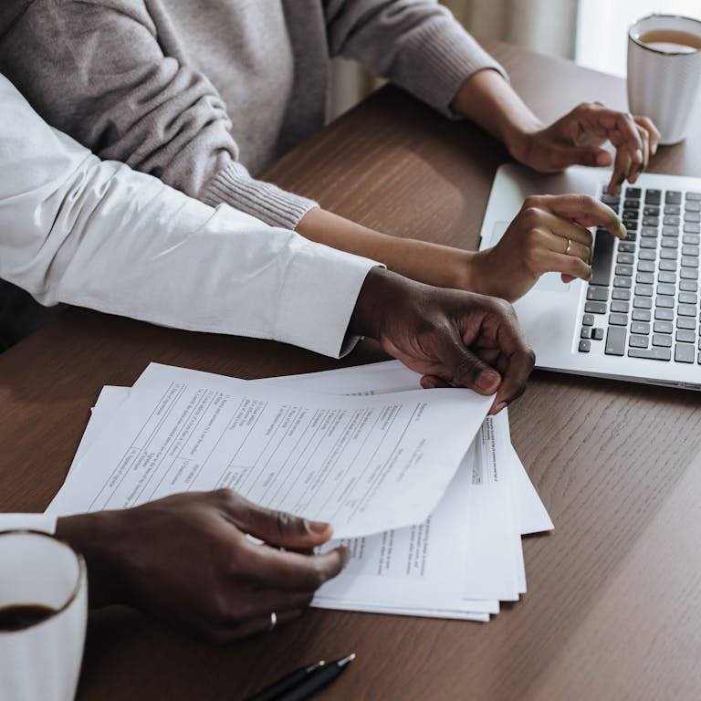Close-up of diverse colleagues working together on a laptop in a modern office environment.