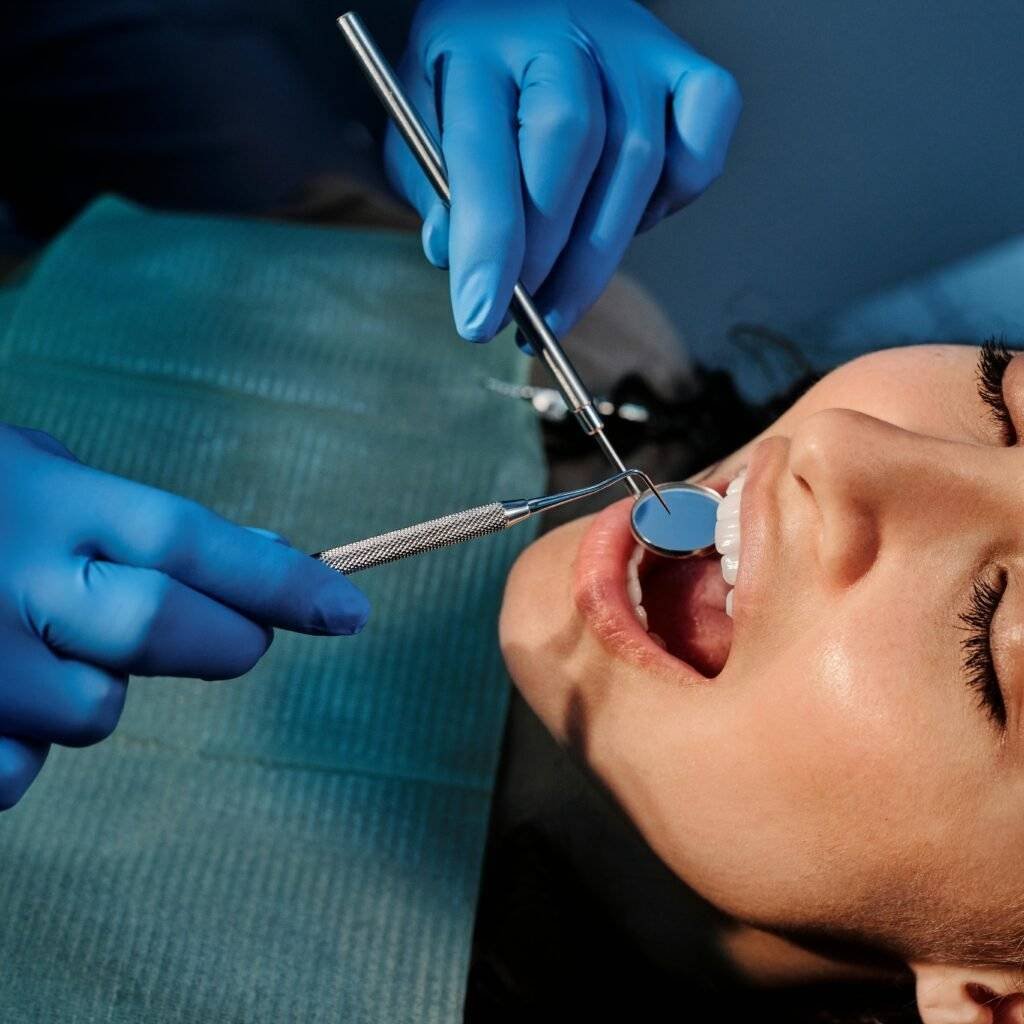 Close-up of a dentist examining a patient's teeth using dental tools.